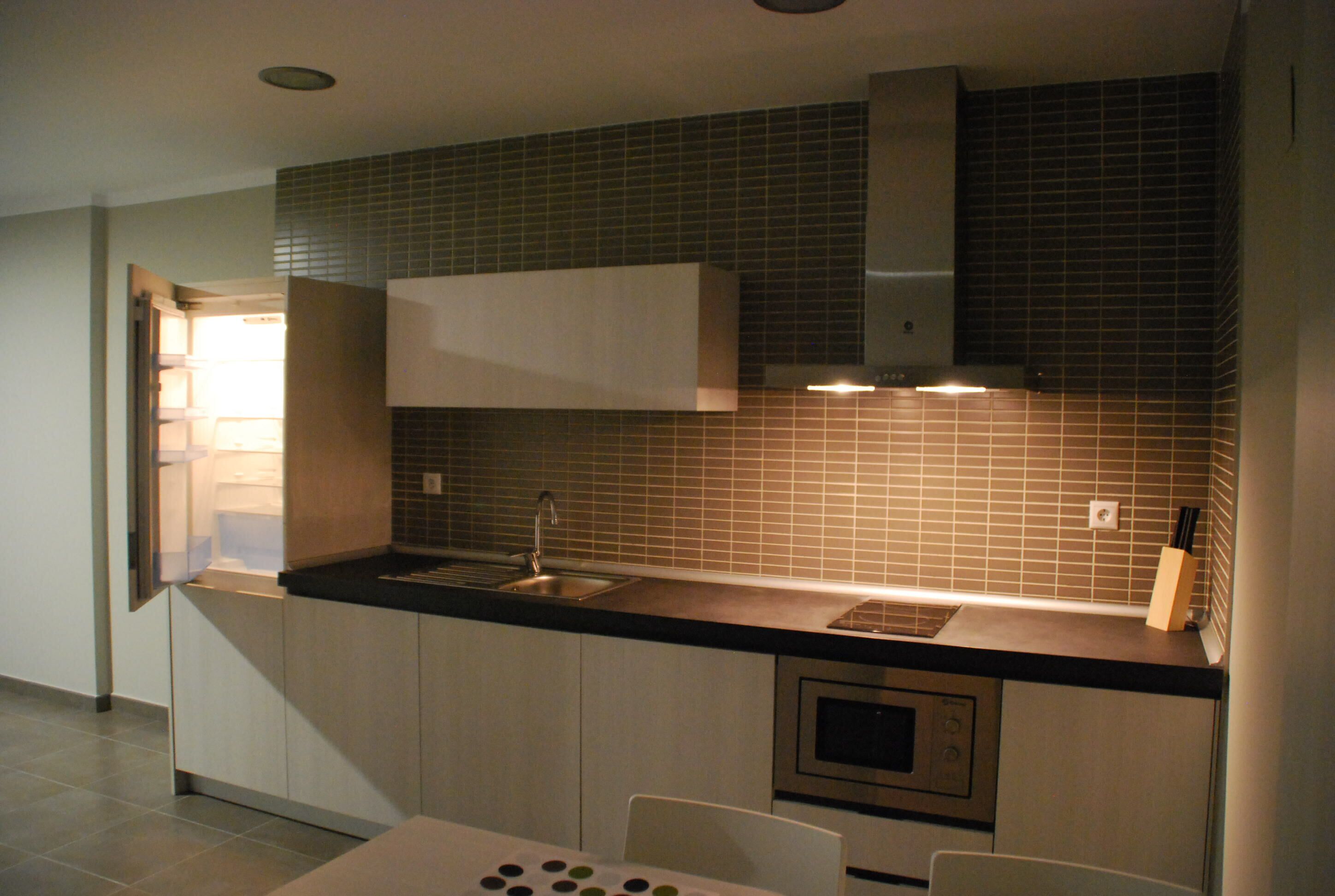 Cozinha moderna com forno embutido, pia e micro-ondas.