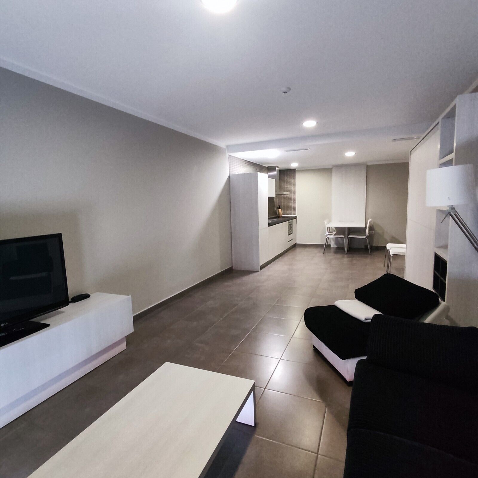 A modern living room with a flat-screen TV, a sofa, and a coffee table.