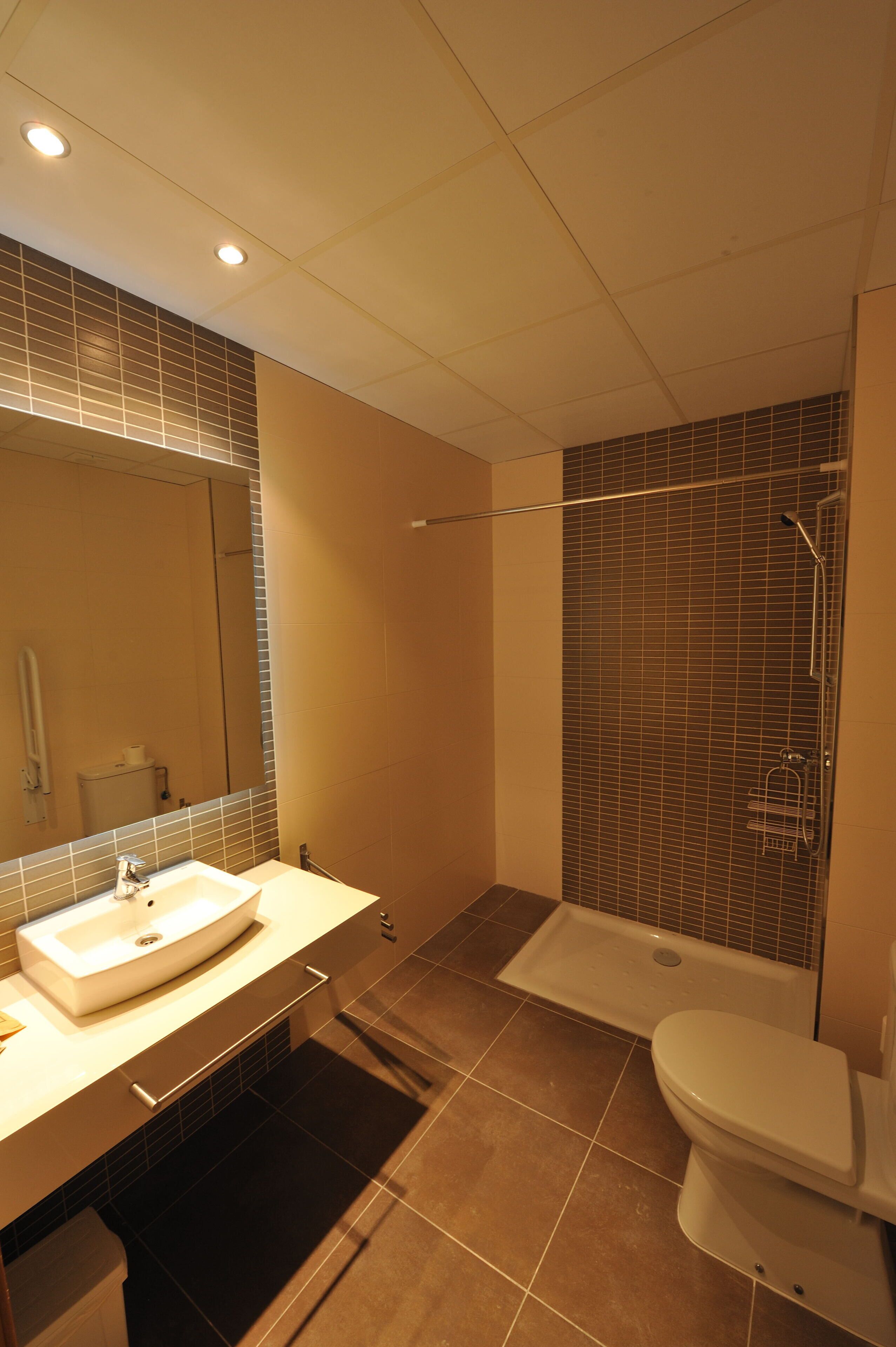 Un baño moderno con un lavamanos grande, un espejo y una zona de ducha separada.