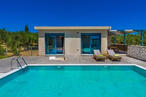 A modern house with a swimming pool, two doors, and a patio with lounge chairs. - Natura Verde Villas (Zakynthos)