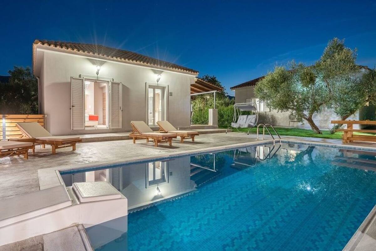 A swimming pool with lounge chairs and a building with a tiled roof.