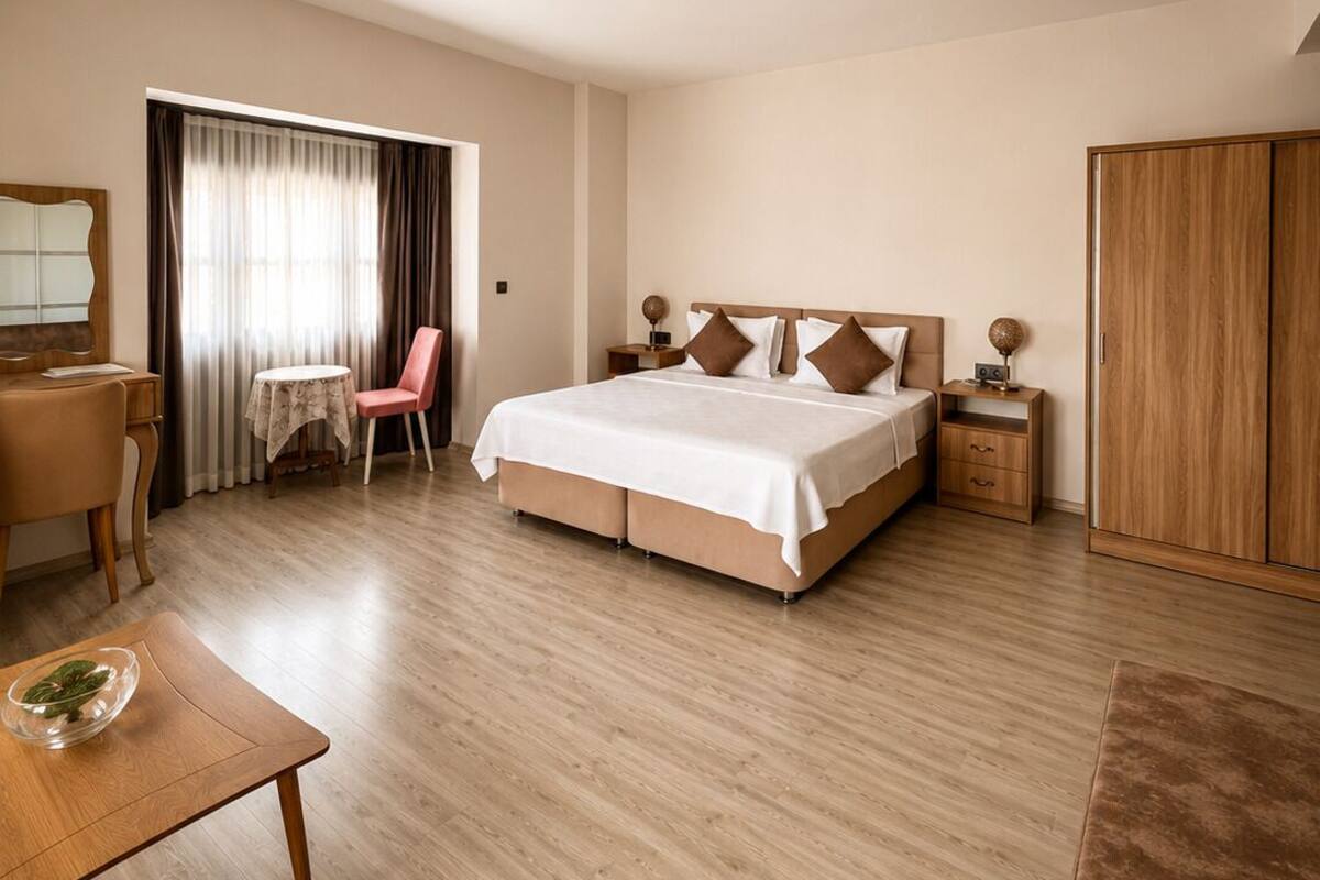 A hotel room with a bed, a desk, a chair, a wardrobe, and a small table with a bowl.