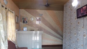 Een receptiegedeelte met een receptiebalie, een klok, ingelijste foto's, een televisie en een behang met een patroon.