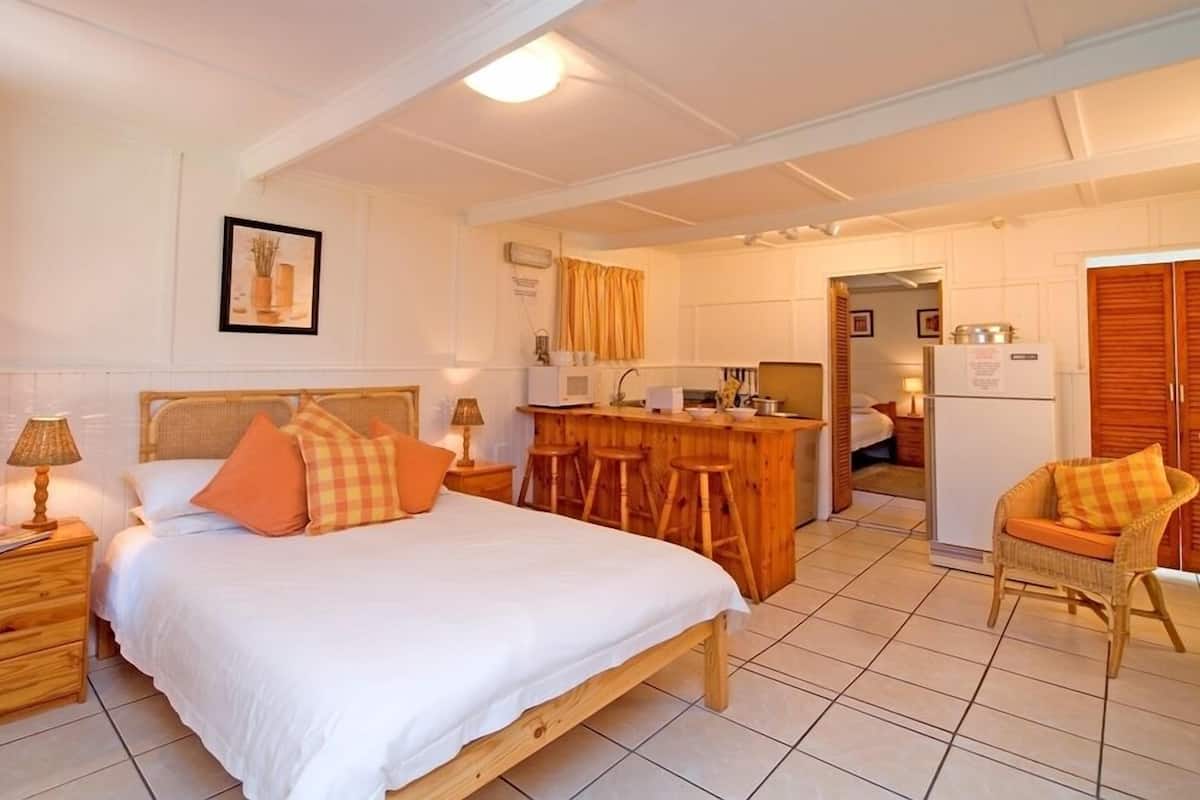 A bedroom with a wooden bed, two nightstands, a bedside table, and a chair.