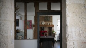 A rustic interior with exposed wooden beams, a brick fireplace, and a dining area with a table and chairs. - La Maison Bleue (Villereal)