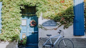 A bicycle parked in front of a building with a blue door and a sign reading "La Maison Bleue MAISON d'HOTES". - La Maison Bleue (Villereal)
