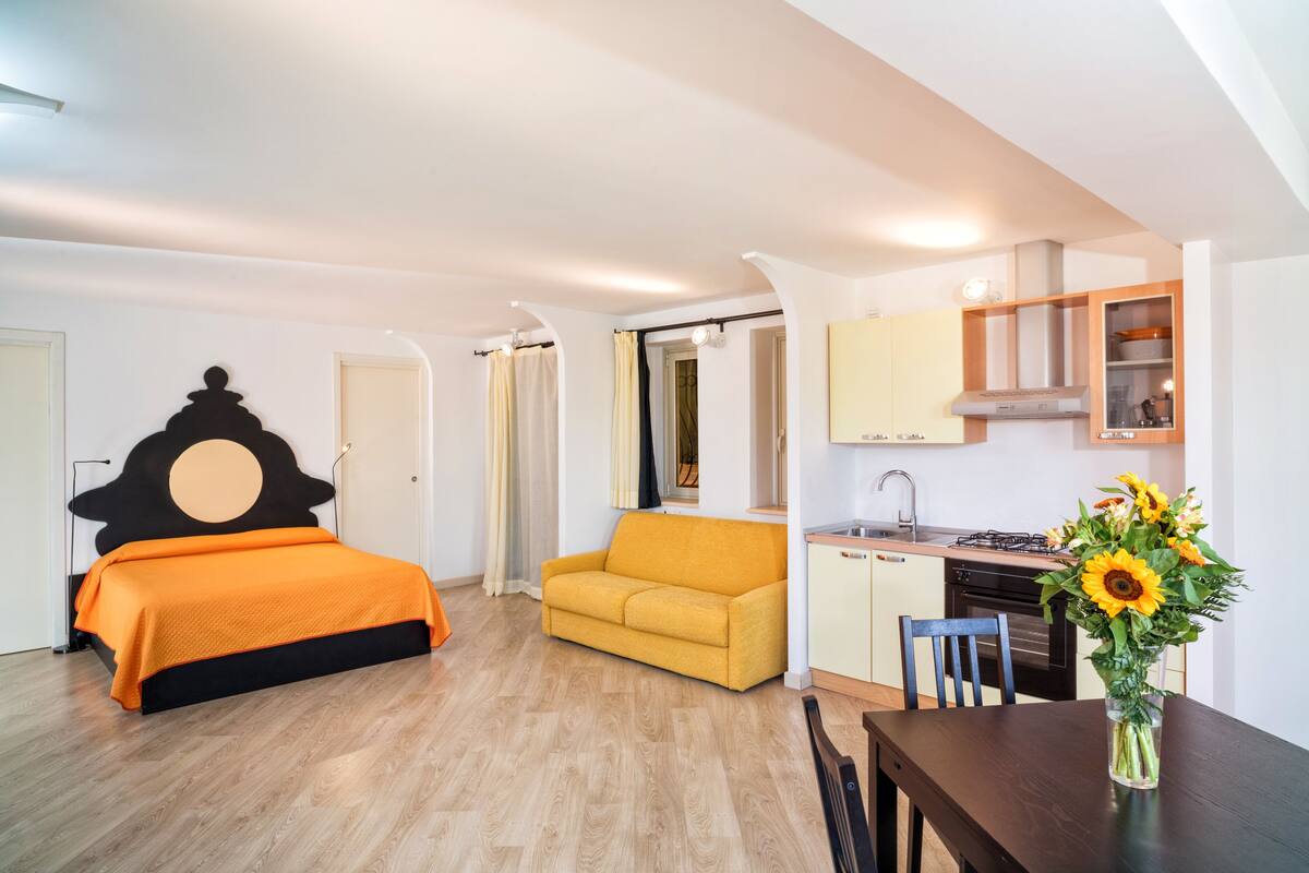 Ein Schlafzimmer mit Bett, Sofa, Esstisch und Küchenzeile.