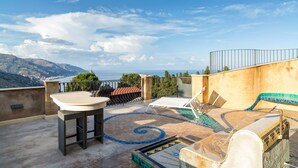 Une terrasse sur le toit avec une piscine, des chaises longues et une table.
