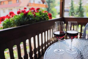 Two wine glasses on a glass table with a view of red flowers and a building in the background. - Hotel-Gasthaus Goldener Engel (Glottertal)