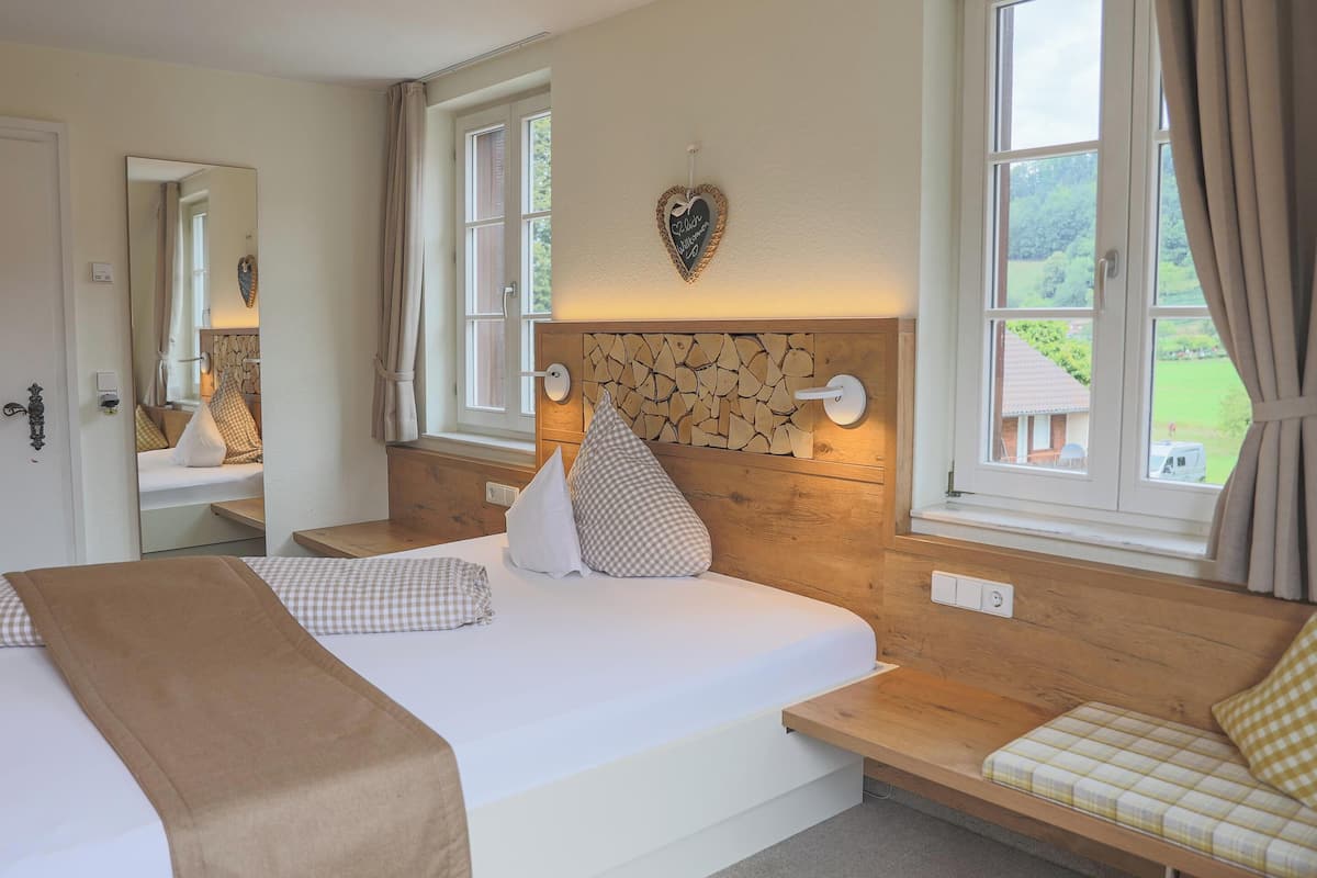 Ein Schlafzimmer mit einem großen Bett, einem Holzkopfende, zwei Nachttischen, einem Spiegel und einem Fenster mit Vorhängen.
