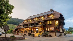 A traditional building with a sloped roof, multiple windows, and outdoor seating area with potted plants. - Hotel-Gasthaus Goldener Engel (Glottertal)