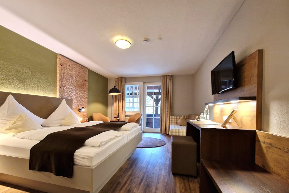Ein Hotelzimmer mit Bett, Schreibtisch, Stuhl, Fernseher und Fenster.