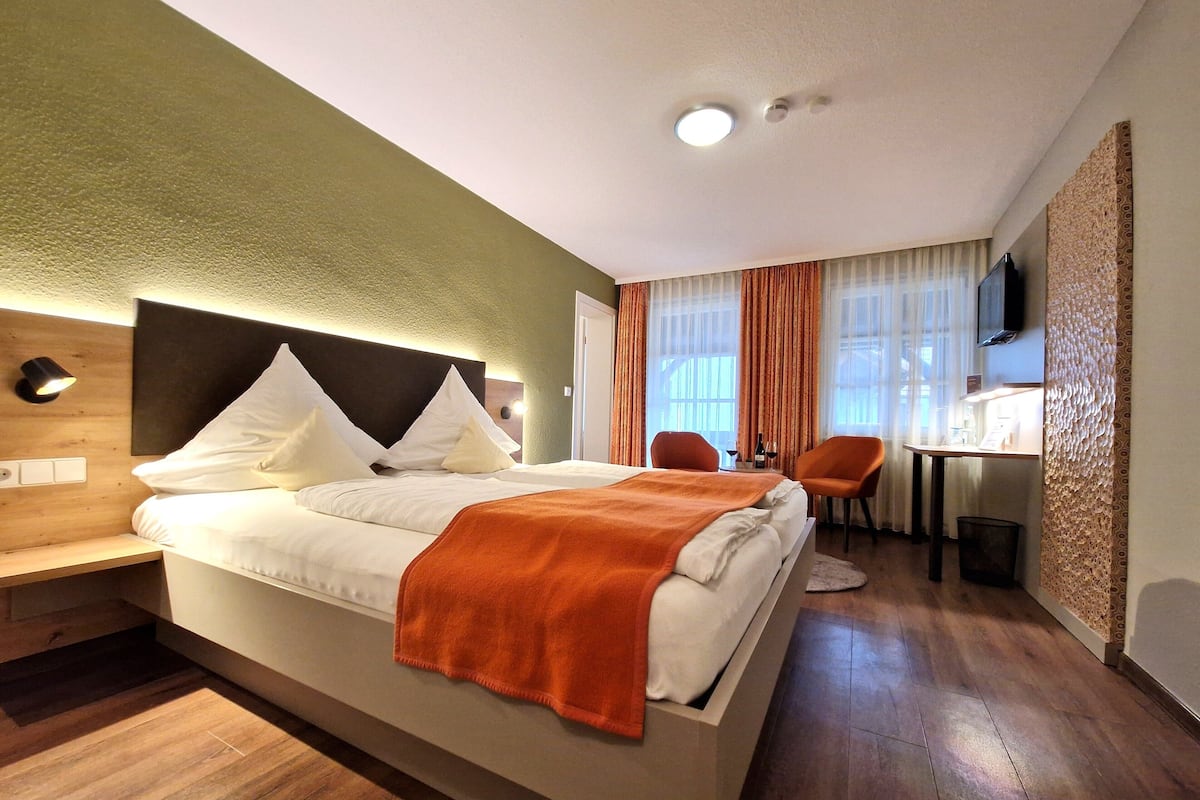 Ein Hotelzimmer mit Bett, Nachttisch und Schreibtisch mit Stuhl.