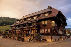 A traditional wooden building with multiple windows and balconies, a covered entrance, and potted plants. - Hotel-Gasthaus Goldener Engel (Glottertal)