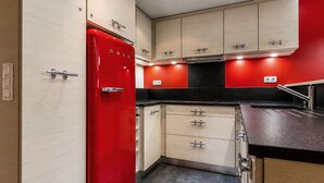 A compact kitchen with a red refrigerator, wooden cabinets, and a black countertop. - 3-room apartment, terrace, pets allowed, garage, village center (La Clusaz)