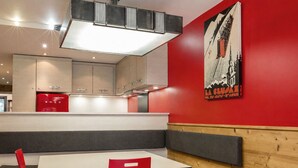 A modern dining area with a white table, red chairs, and a bench. - 3-room apartment, terrace, pets allowed, garage, village center (La Clusaz)
