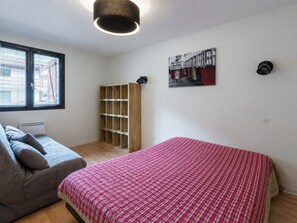 A bedroom with a bed, a sofa, a built-in wardrobe, a ceiling light, and a wall-mounted picture.