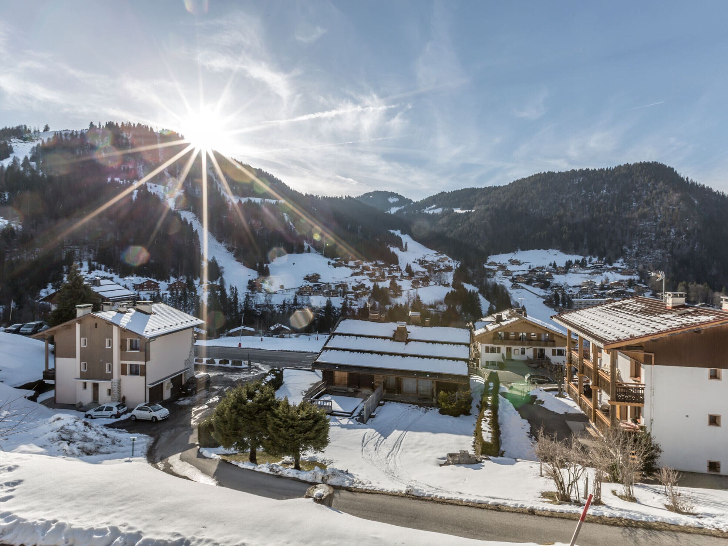 Un pueblo cubierto de nieve con edificios, una carretera y una montaña al fondo.