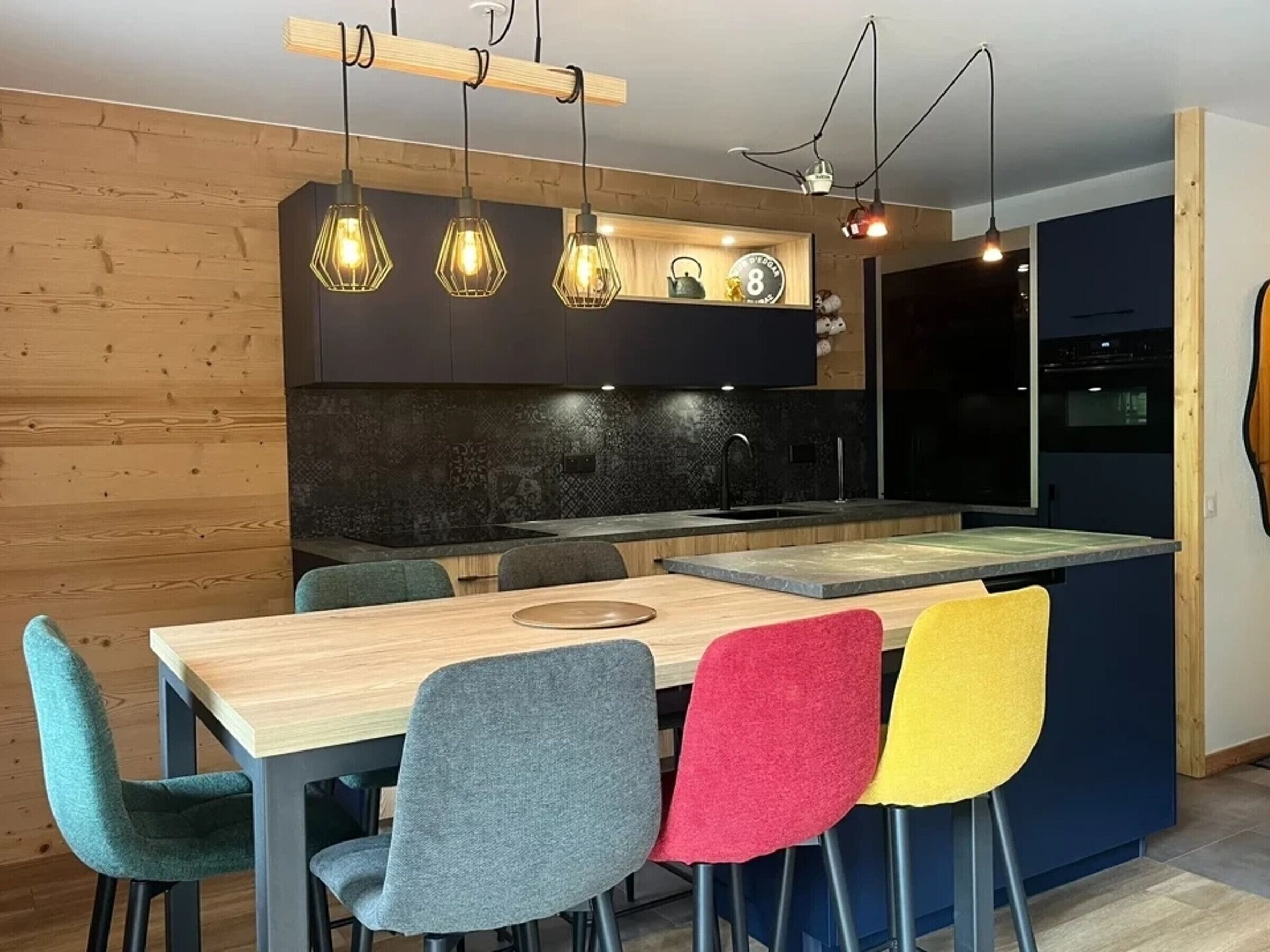 Une cuisine moderne dotée d’un îlot central, de meubles en bois et de luminaires suspendus.