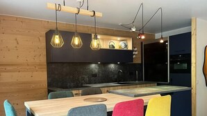 Une cuisine moderne dotée d’un îlot central, de meubles en bois et de luminaires suspendus.