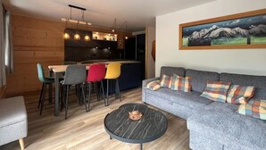 Un salon moderne comprenant un canapé, une table basse et un coin repas avec des chaises.