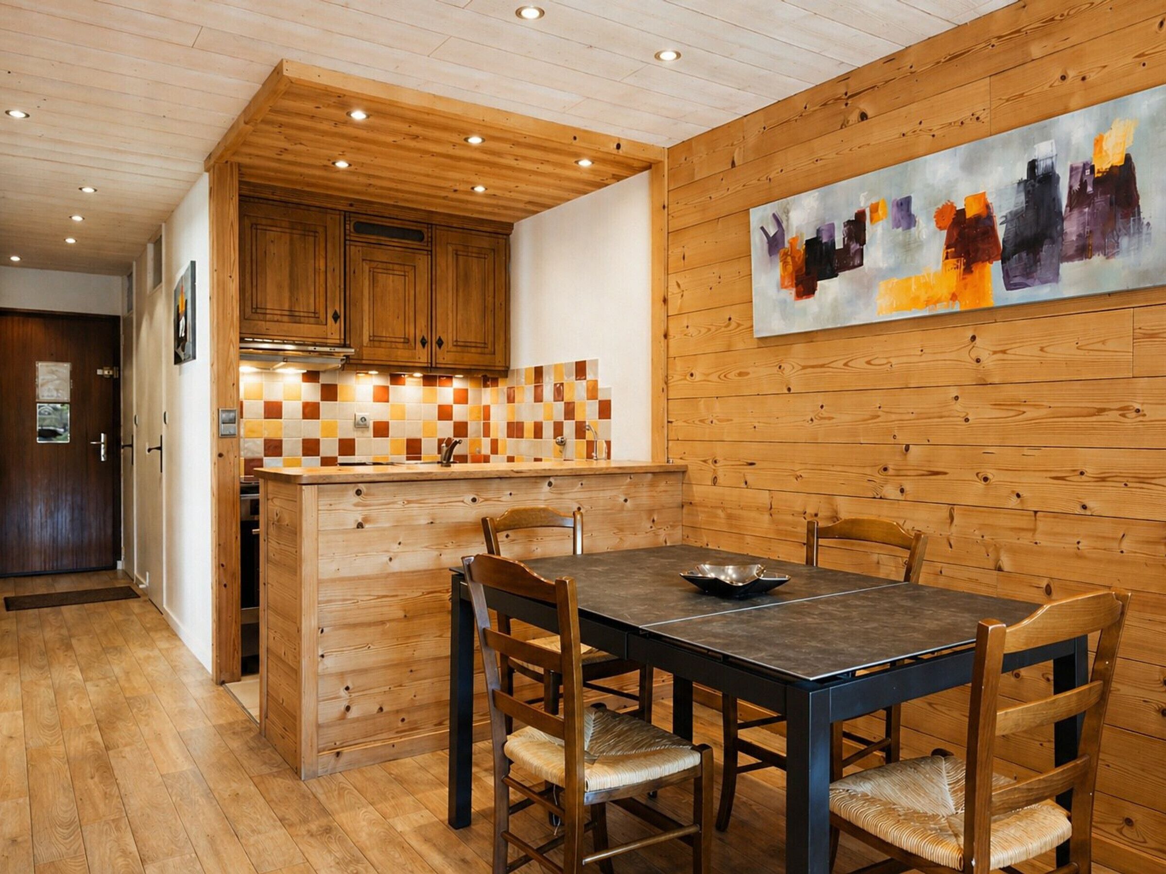 A wooden interior with a kitchen, dining table, and chairs.