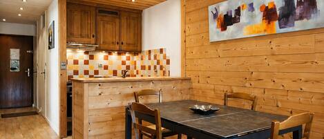 A wooden interior with a kitchen, dining table, and chairs.