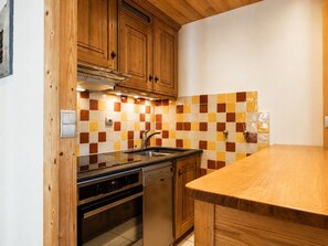 Eine Küche mit Holzschränken, einer Fliesenrückwand, einer Edelstahl-Spüle und einer Holzausziehtafel.