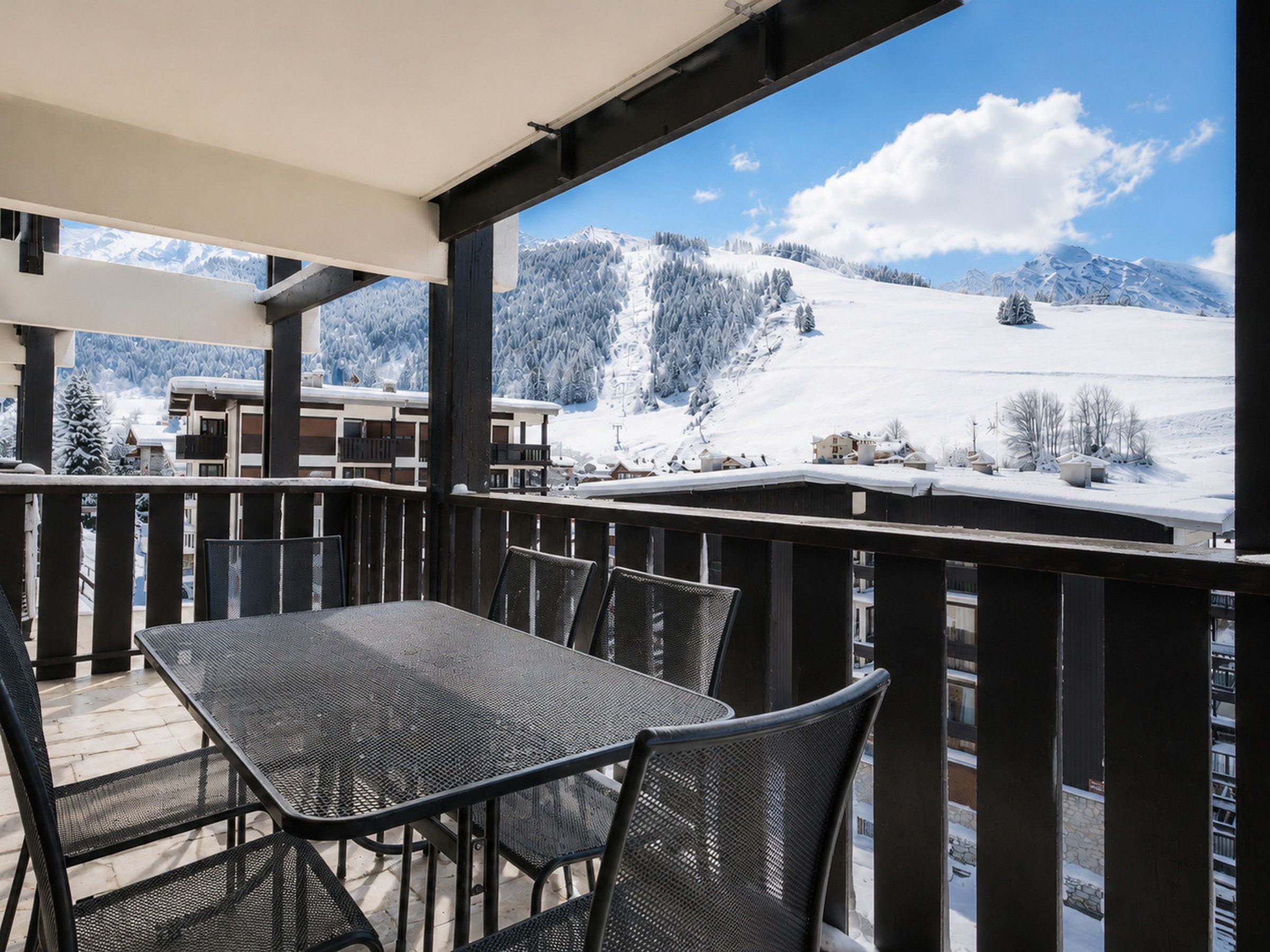 A balcony with a table and chairs overlooking a snowy mountain landscape.