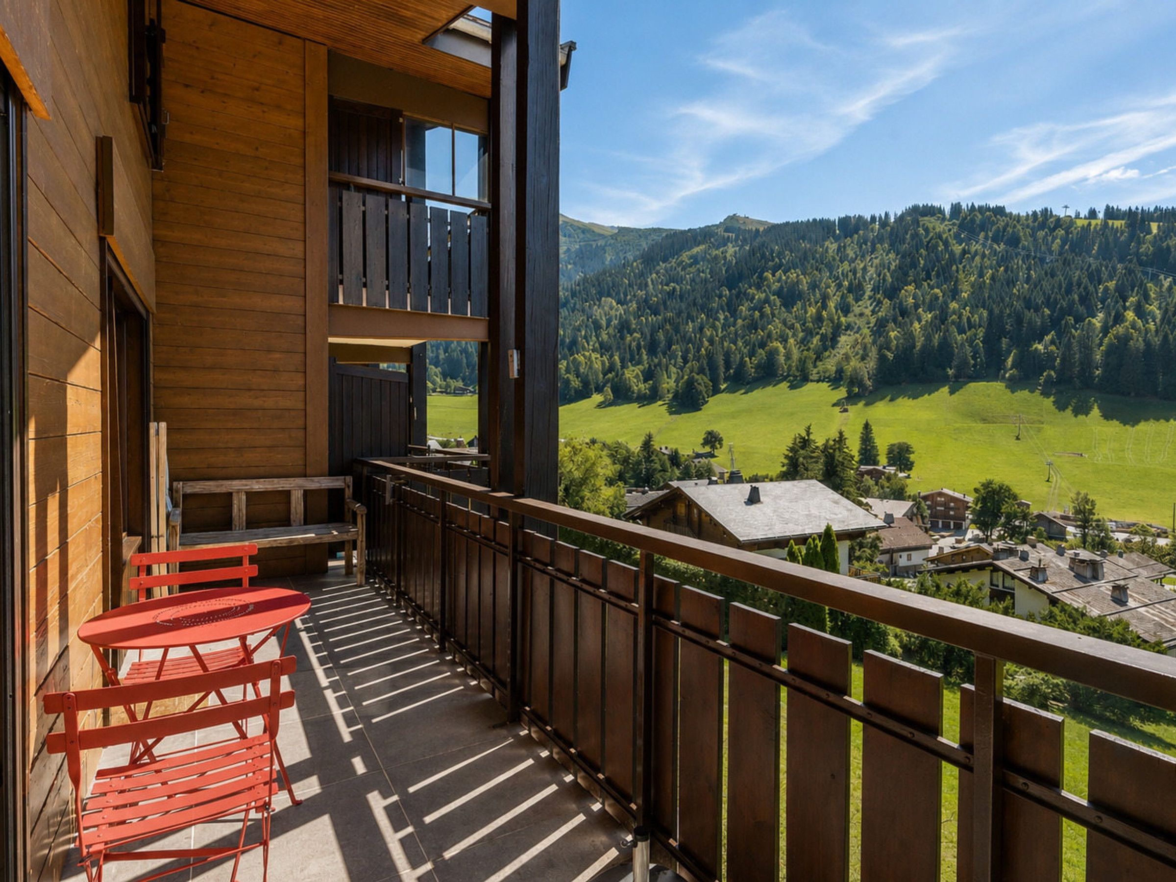 Un balcon donnant sur une vallée verdoyante et des collines boisées.