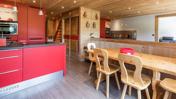 A modern kitchen with wooden cabinets, a red island, and a dining area with wooden chairs and a table. - Spacious apt 7 ppl, 3*, quiet, La Clusaz (La Clusaz)