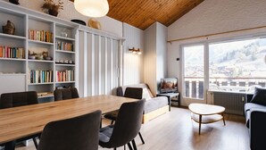 A modern living room with a wooden ceiling, a dining area, and a large window with a mountain view. - Charming studio near slopes, pets allowed (La Clusaz)