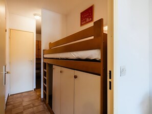 Una cama litera con escalera, una puerta y un interruptor de luz en la pared.