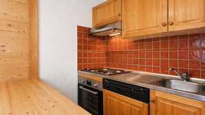 A kitchen with wooden cabinets, a tiled backsplash, a stove, a dishwasher, and a sink. - Perfect ski location, 6 guests, pets, garage, WIFI (La Clusaz)