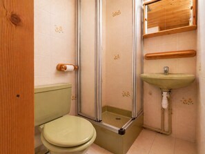 A bathroom with a toilet, a shower enclosure, and a sink.