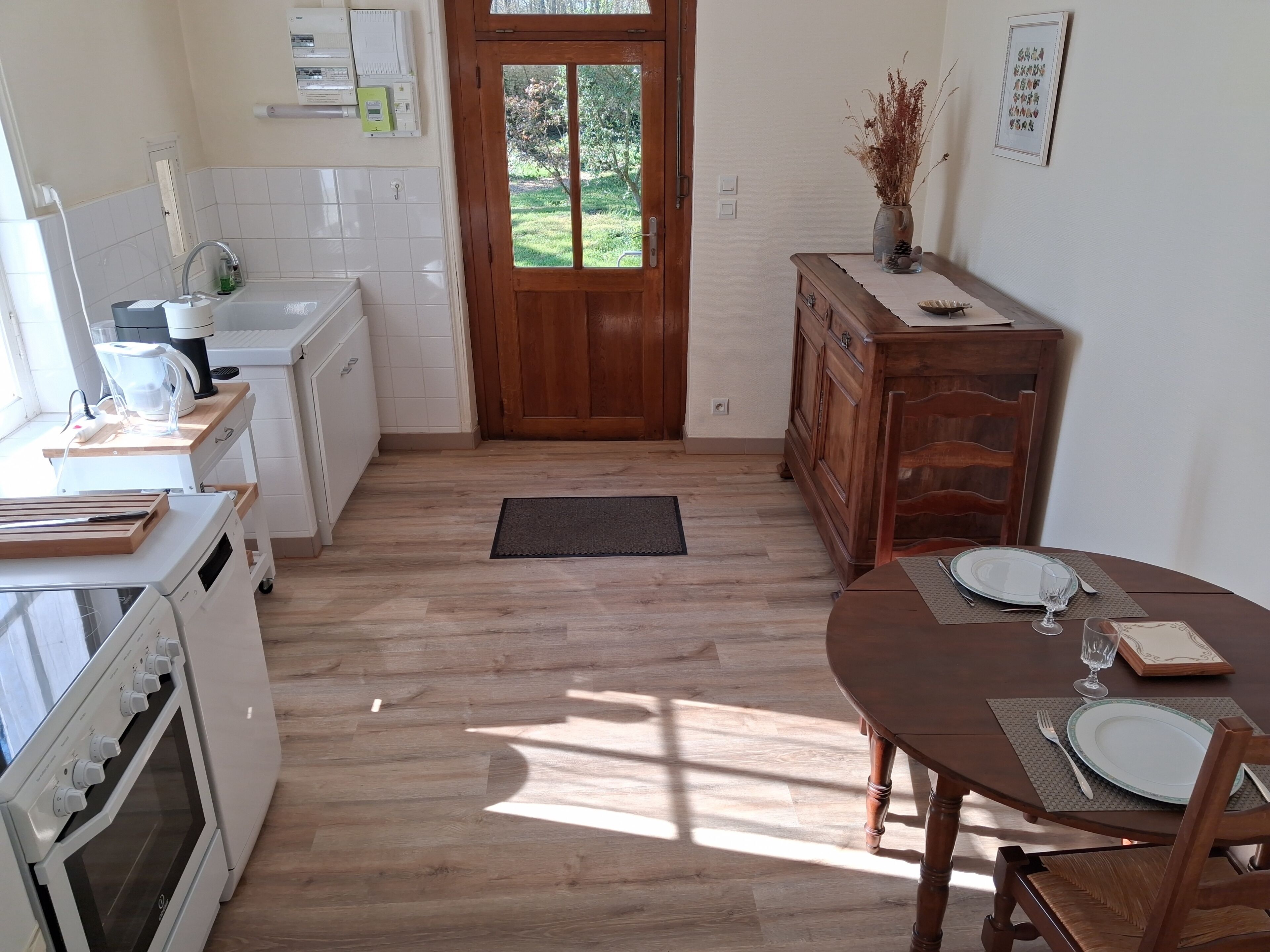 Een keuken met een houten deur, een eettafel gedekt met borden en bestek, en een kookplaat.