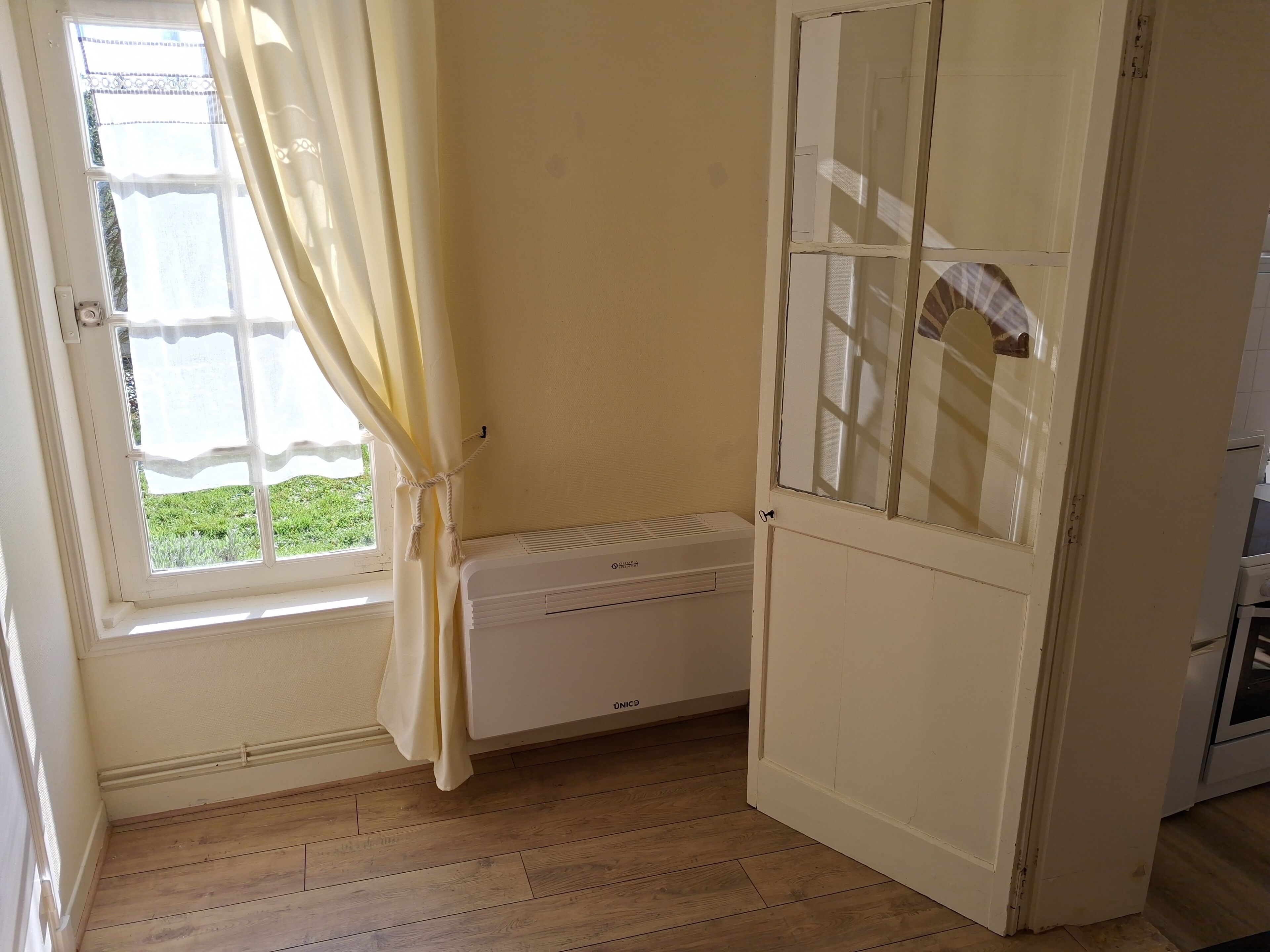 A room with a window, a radiator, and a door.