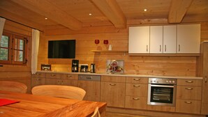 A wooden interior with a kitchen area featuring cabinets, a coffee maker, and a built-in oven. - Haus Anni im Paradies (Kiefersfelden)