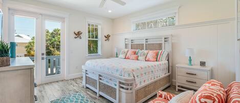 A bedroom with a bed, a nightstand, a dresser, a window, and a ceiling fan.