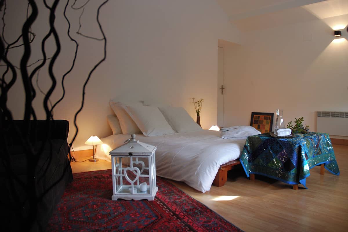 A bedroom with a bed, bedside table, lamp, and decorative items.