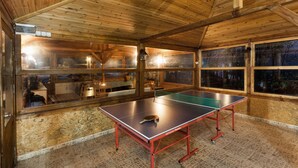 A ping pong table in a wooden room with large windows and a tiled floor. - Karaca Dag Evleri (Basiskele)