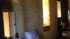 Un dormitorio con pared de ladrillo, cama con ropa de cama floral y techo de madera.