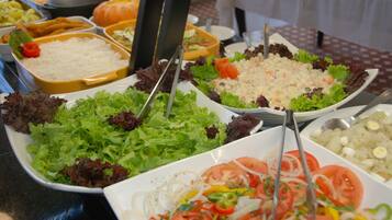 Un bufé con diversos platos, incluyendo ensaladas, arroz y otros alimentos preparados.