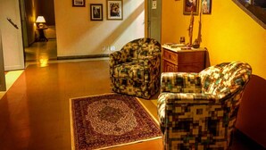 Un couloir avec un fauteuil à motifs, une petite table et un tapis.