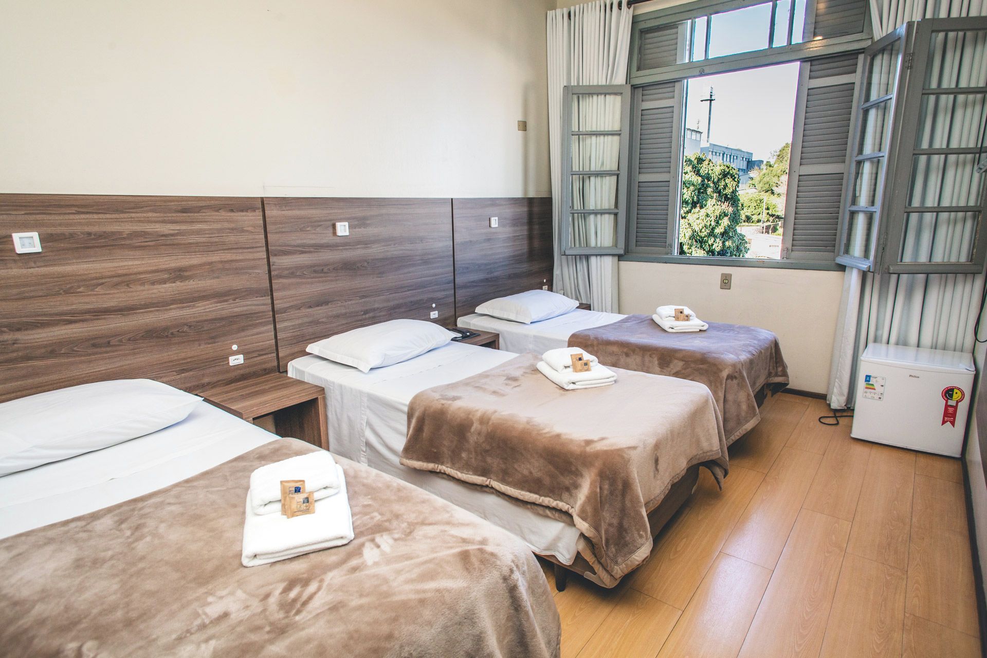 Une chambre d’hôtel avec deux lits, une fenêtre avec des rideaux et un minibar.