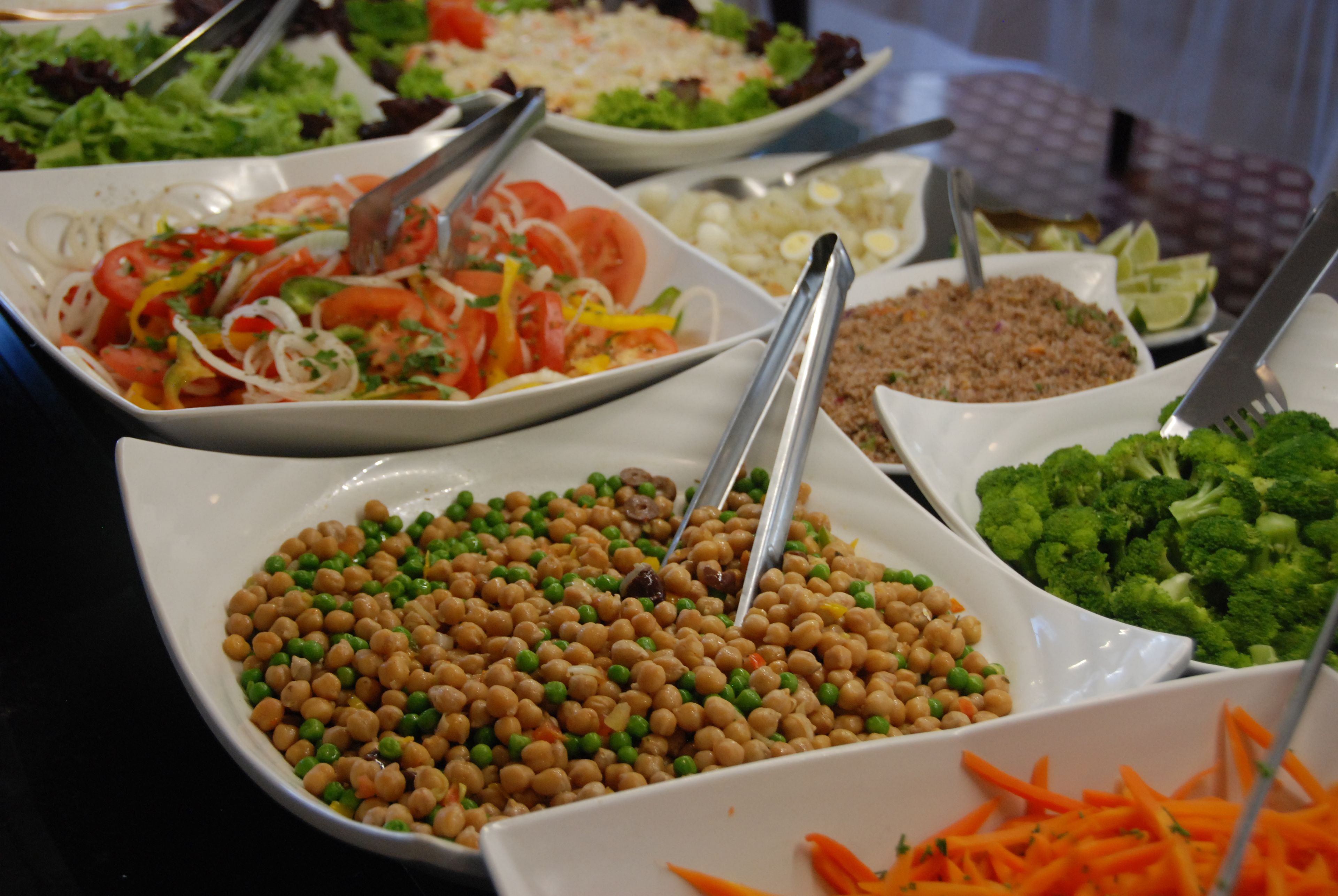 A buffet with various dishes including salads, chickpeas, and vegetables.