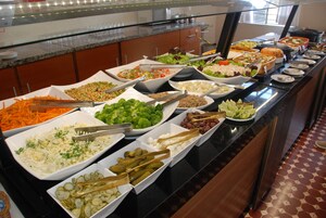 Un bufé con una variedad de platos, incluyendo ensaladas, verduras y carnes.