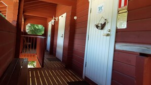 A corridor with wooden walls and doors, a wooden railing, and a fire extinguisher sign. - Miekkala Majoitus (Lappeenranta)