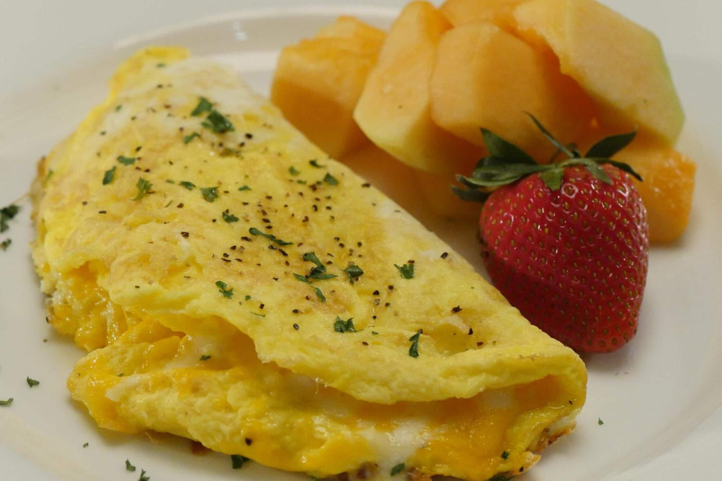 Una frittata con erbe aromatiche, una fragola e melone su un piatto.