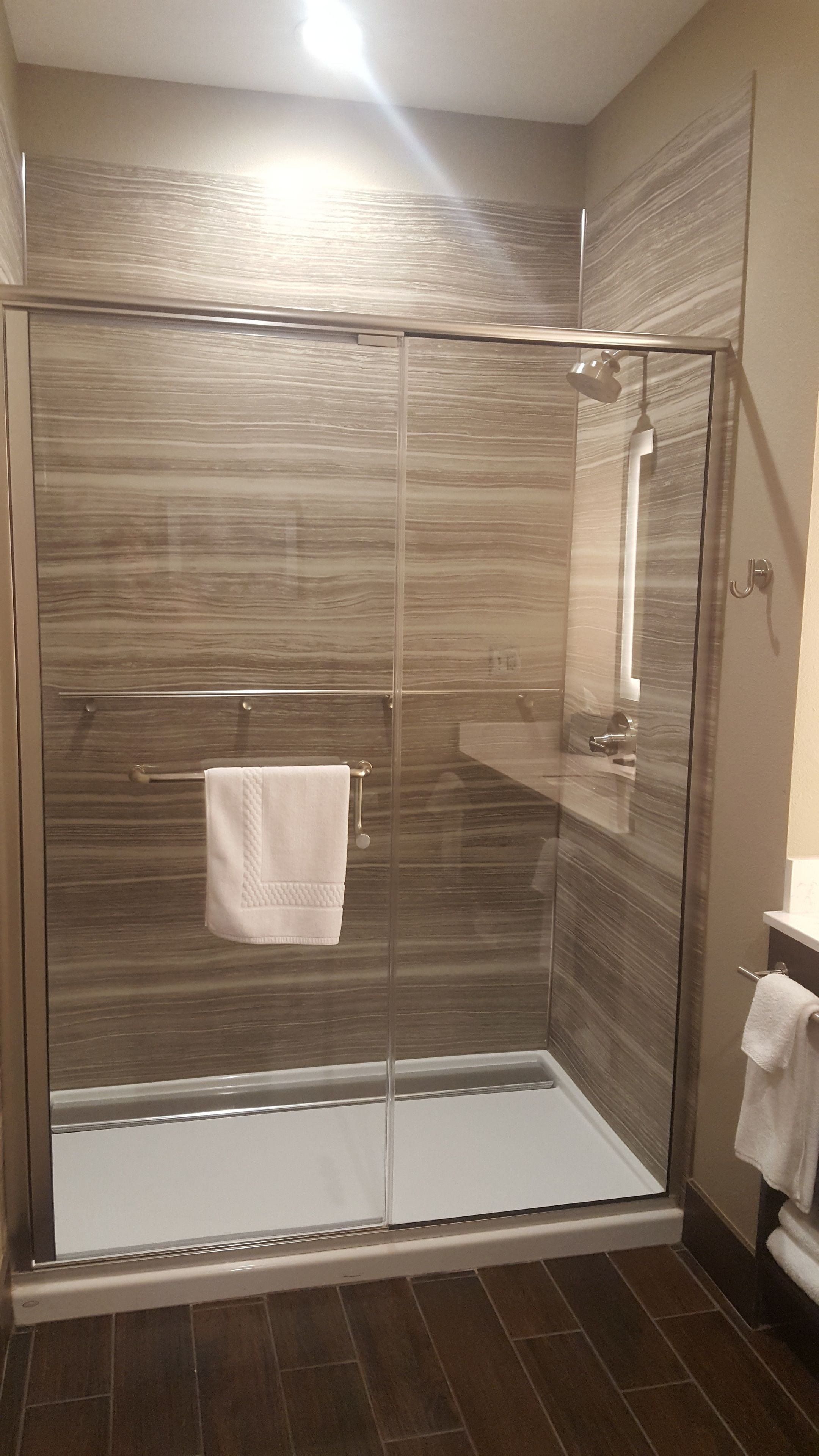 A glass-enclosed shower with a towel rack and a glass door.